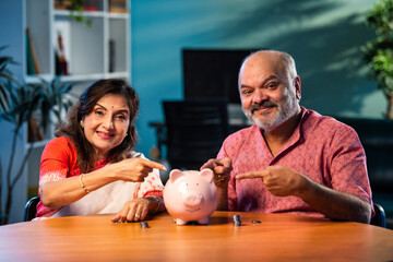 Elderly Indian couple managing savings with coins and piggy bank, planning secure financial future