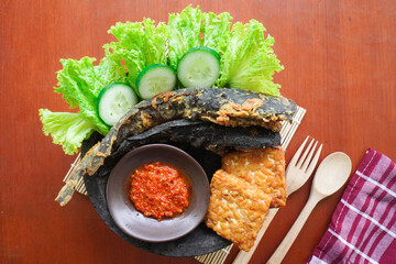 Pecel lele or pecak lele or penyetan consisting of catfish, tempeh, tomato sambal, catfish fried then served fresh vegetables, cucumbers, cabbage