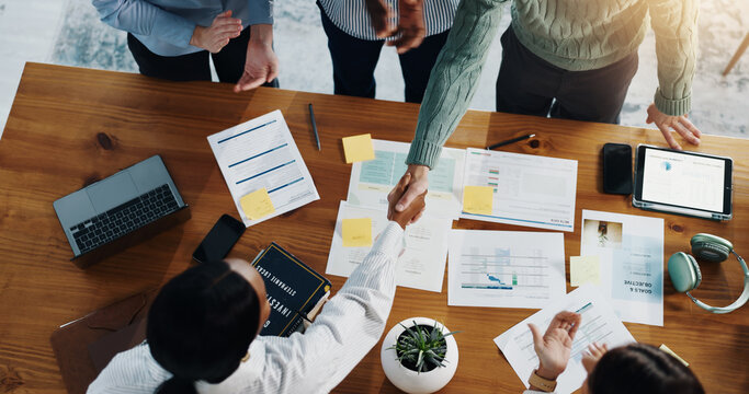 Handshake, finance documents and business people in office for deal, negotiation or partnership. Shaking hands, top view and financial advisors with client for investment meeting in workplace.