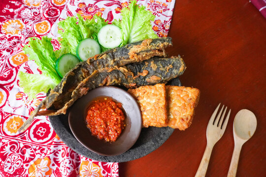 Pecel lele or pecak lele or penyetan consisting of catfish, tempeh, tomato sambal, catfish fried then served fresh vegetables, cucumbers, cabbage