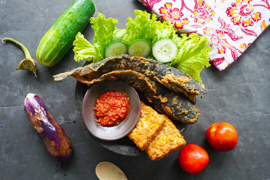 Pecel lele or pecak lele or penyetan consisting of catfish, tempeh, tomato sambal, catfish fried then served fresh vegetables, cucumbers, cabbage
