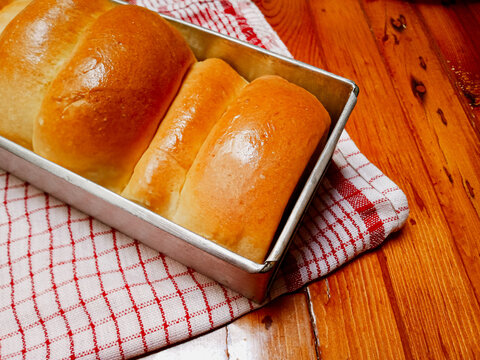 Fresh homemade and shiny Roti sobek, gembong or kasur, soft sweet milk bun, in wooden brown background.
