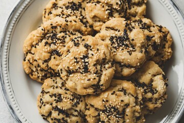 A photo of a white plate with sweet cookies with sesame seeds