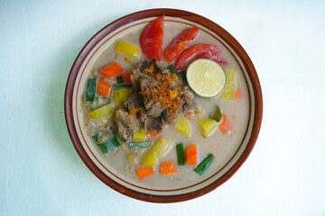 Soto Betawi is a traditional food from Jakarta, consisting of a mixture of coconut milk and milk sauce, meat, offal, carrots, potatoes, lime and spices. on white background