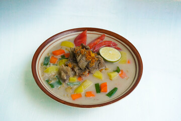 Soto Betawi is a traditional food from Jakarta, consisting of a mixture of coconut milk and milk sauce, meat, offal, carrots, potatoes, lime and spices. on white background