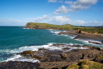 Scenic Coastal View with Rocky Shores and Green Hills