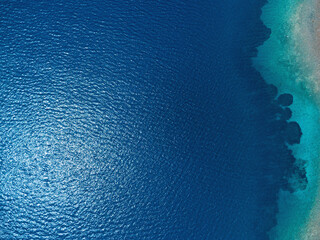 Turquoise water surface with dark seabed formations visible from above, creating a beautiful...