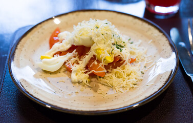 mix of tomatoes, cheese, eggs with mayonnaise on a plate in a restaurant