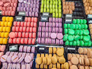 A vibrant display of french macarons in various colors, arranged neatly in trays, highlighting...