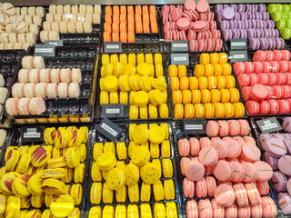 Colorful assortment of macarons displayed in trays, featuring vibrant hues of yellow, pink, orange, and purple
