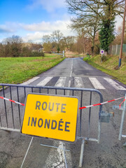 Road closure sign in French indicating flooded area, with barriers blocking access, surrounded by...