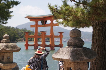 観光客と石灯籠越しの厳島神社大鳥居