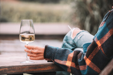 Woman holding glass of chilled white wine sitting at wooden table enjoying relaxing day in the...