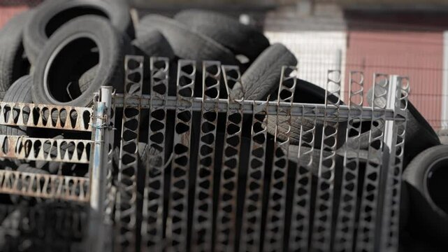A lot of old automotive road radial wheels tires are lying around in illegal landfill in public place, garages. Trash site, litter. Passenger vehicle spare parts.