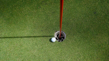 Obraz premium Golf ball is on a green lawn in a beautiful golf course with morning sunshine.