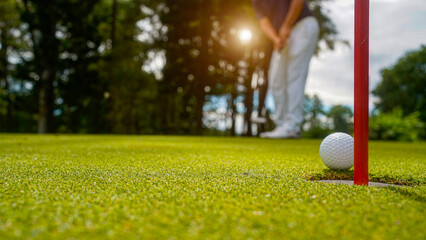 Golfer putting ball on the green golf, lens flare on sun set evening time.
