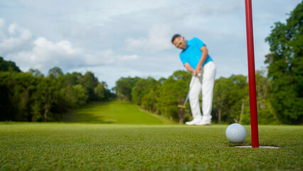 Golfer putting ball on the green golf, lens flare on sun set evening time.