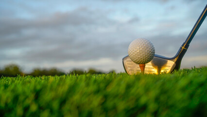 Golf clubs and balls on a green lawn in a beautiful golf course with morning sunshine.