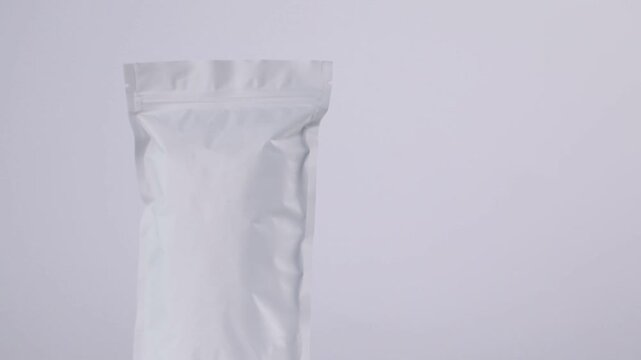 Zipper stand-up pouch spinning on light grey background, closeup. Space for text
