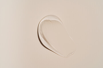 Pure transparent cosmetic gel smear on beige background, skin care glycerin texture. top view....