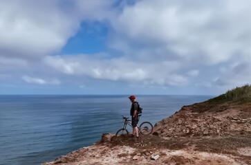Cyclist standing on the edge of cliff