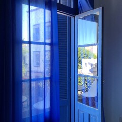 Blue - painted window with sheer blue curtains, creating a cohesive, dreamy blue ambiance. Blends...