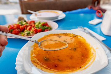 Close up of a spoon lifting a portion of Tarhana soup, a traditional Turkish dish, in a vibrant restaurant setting