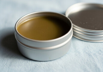 Homemade Herbal Balm in Metal Tin on Light Blue Fabric