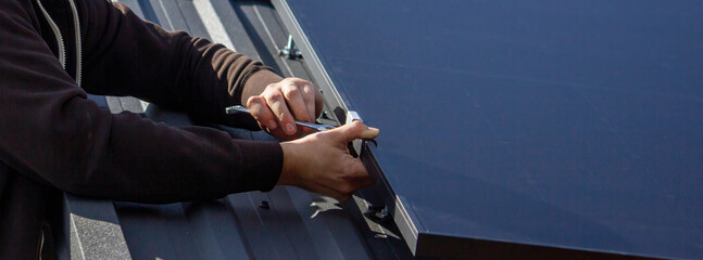 A man is installing solar panels on a roof. Selective focus