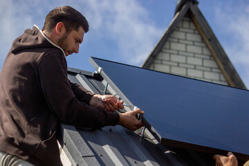 A man is installing solar panels on a roof. Selective focus
