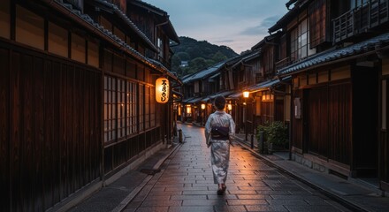 Fototapeta premium Woman in Kimono Walking Down a Traditional Japanese Street at Dusk