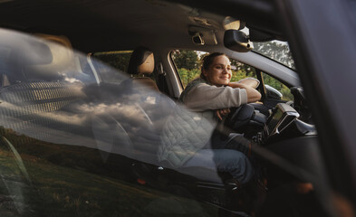Happy young woman drivier looking out of car window, auto travel and adventure