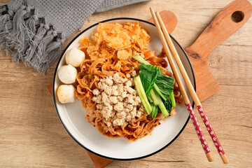 Spicy Asian Chili Oil noodles with minced chicken, fish balls, and vegetables served on plate. Perfect for recipes, articles or any cooking content.