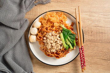 Spicy Asian Chili Oil noodles with minced chicken, fish balls, and vegetables served on plate. Perfect for recipes, articles or any cooking content.