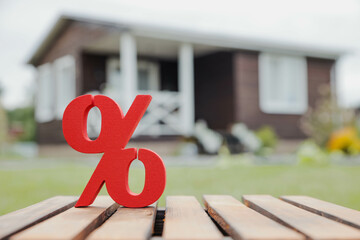 Wooden house on the background of a red percentage sign, representing mortgage rates, real estate...