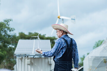Man with solar panels  and wind turbine on background in smart farm