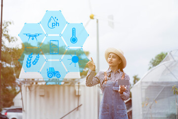 Woman push tool on screen in smart farm with solar panels  and wind turbine on background.