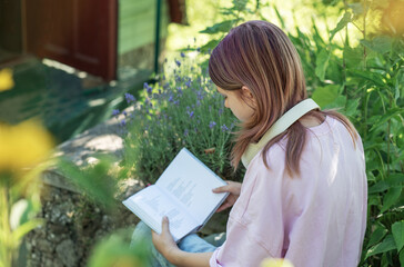 Young woman reading a book in a garden surrounded by lavender