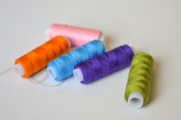 colorful spools of thread lined up on a white surface great for themes like sewing, textile arts,...