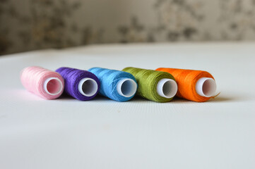 colorful spools of thread lined up on a white surface great for themes like sewing, textile arts,...
