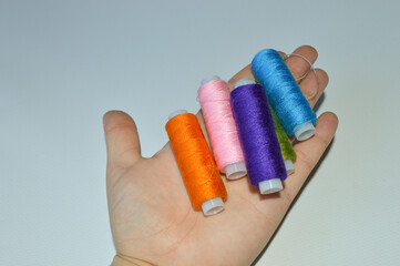 colorful spools of thread lined up on a white surface great for themes like sewing, textile arts,...
