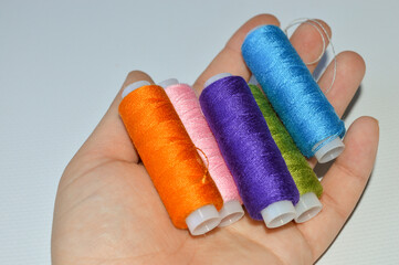 colorful spools of thread lined up on a white surface great for themes like sewing, textile arts,...