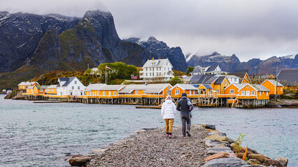 Couple walking to traditional rorbuer cabins in Sakrisøy, Lofoten Islands, Norway