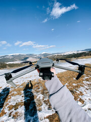 Enthusiast prepares to fly drone in snowy mountain landscape during bright sunny day