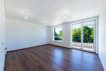 Modern Empty Room With Wooden Floor and Large Windows Overlooking Greenery