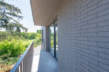 Modern Balcony Overlooking Greenery with Iron Railing and Brick Walls in Daylight