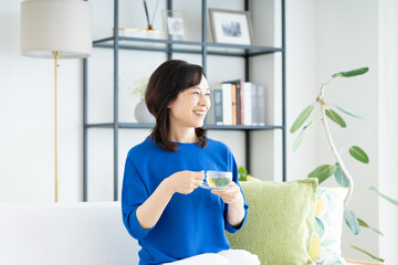 リビングでハーブティーを飲むミドルの女性