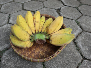 Yellow ripe Kepok Banana atau pisang kepok matang on wicker bamboo basket isolated on grey paving background. top view