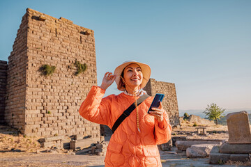 Happy tourist visiting the ruins of Assos in Turkey and using smartphone app as audio guide
