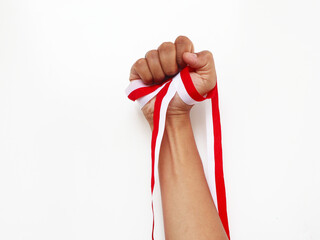 The hands of a man holding a red and white ribbon as a symbol of the Indonesian flag. Isolated on white background. Independence day concept